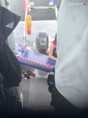 zdjęcie kolorowe fragment policjanta i osoby wchodzącej na łódź policyjną