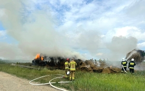 strażacy gaszą płonąca stertę balotów