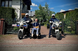dwaj policjanci na motocyklach, pomiędzy nimi Wojtek na wózku