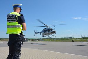 na pierwszym planie policjant, w tle śmigłowiec