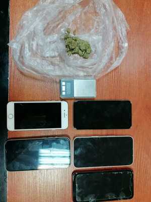 na blacie leżą cztery telefony komórkowe, elektroniczna waga i marihuana w foliowym woreczku
