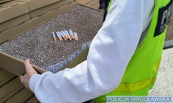 policjant trzyma karton wypakowany papierosami