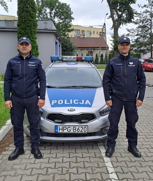 dwóch policjantów stojących przy radiowozie
