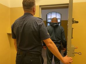 policjant stoi przed celą, w środku zatrzymany