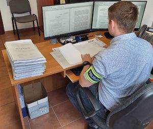 nieumundurowany funkcjonariusz siedzi przy biurku, pisze na klawiaturze komputera