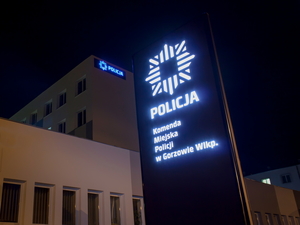 Pora nocna. Pylon informacyjny z napisem Komenda Miejska Policji w Gorzowie Wlkp., w tle budynek komendy