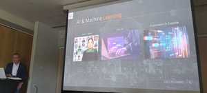 mężczyzna -prelegent oraz widoczny ekran z wyświetlonym slajdem dotyczącym omawianych na forum treści