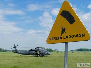 na trawie stoi black hawk, przed nim znak strefa lądowań