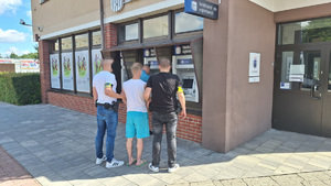 policjanci po cywilnemu wraz z zatrzymanym mężczyzną na tle bankomatów