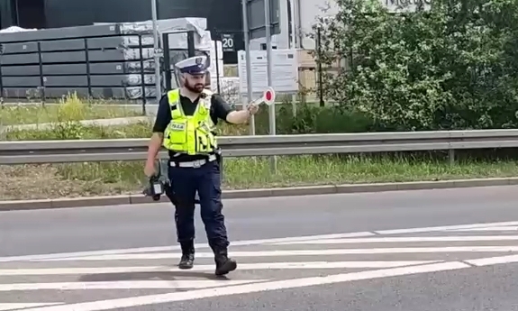 policjant ruchu drogowego na drodze, w dłoni trzyma tzw. lizak