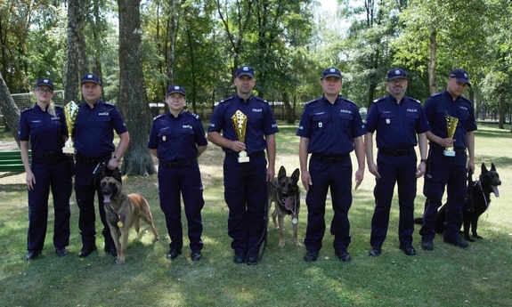 policjanci, którzy brali udział w mistrzostwach z psami służbowymi, trzymają puchary