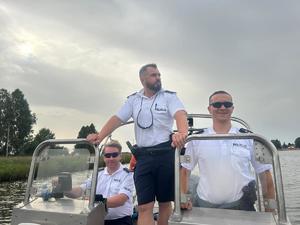 trzech policjantów stoi na łódce