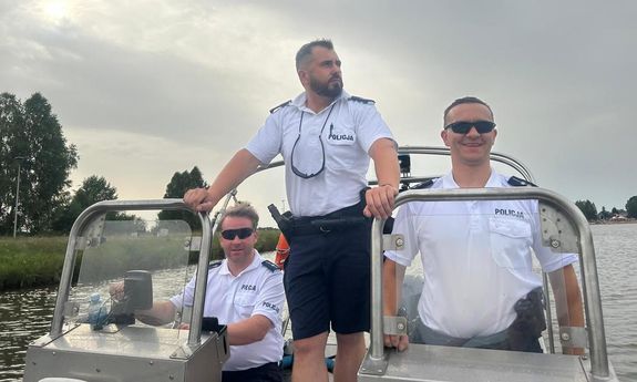 trzech policjantów stoi na łódce