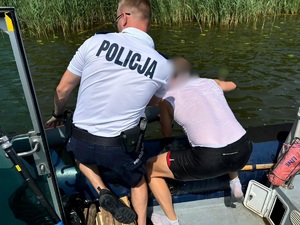 policjant pomaga mężczyźnie wyciągnąć kajak z wody