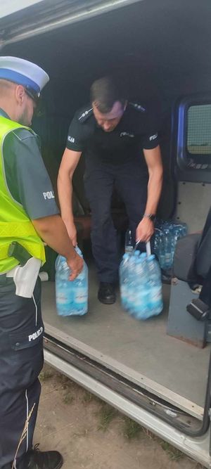 policjanci niosą wodę dla pasażerów pociągu