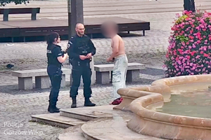 Stopklatka z monitoringu miejskiego przedstawia mężczyznę, który rozmawia z dwójka policjantów