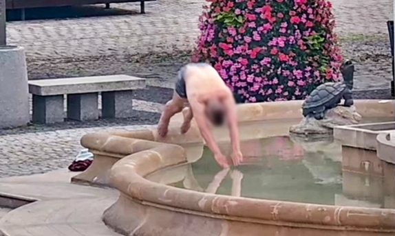 Stopklatka z monitoringu miejskiego przedstawia mężczyznę, który wskakuje do fontanny