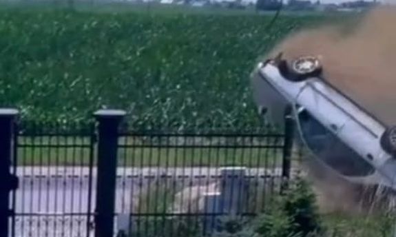 koziołkujący samochód na jezdni przy ogrodzeniu posesji