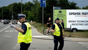 policjant ruchu drogowego kieruje ruchem drogowym, za nim widoczny jest innym umundurowany policjant, a z tyłu plakat promujący Open&#039;er Festival