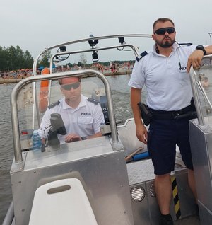Dwaj policjanci na łodzi, patrolują zbiornik wodny.