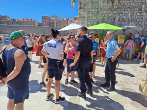 Trójka umundurowanych policjantów podczas rozmowy z grupą turystów.