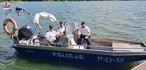 trzech policjantów na łodzi motorowej ubranych w mundury- białe koszulki z napisem Policja i spodnie