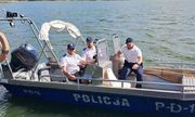 trzech policjantów na łodzi motorowej ubranych w mundury- białe koszulki z napisem Policja i spodnie