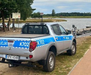 policyjny radiowóz stoi nad brzegiem zbiornika wodnego