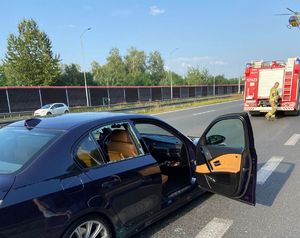 Na zdjęciu samochód, wozy strażackie, policjanci i strażacy na autostradzie, widoczny parawan czerwonego koloru