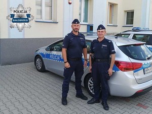 policjanci stoją przy radiowozie