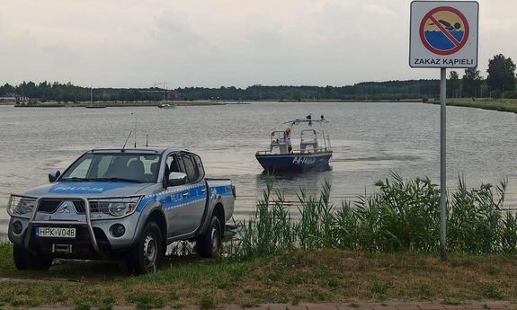 radiowóz na brzegu i łódka policyjna na wodzie