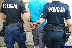 dwaj policjanci prowadzą zatrzymanego