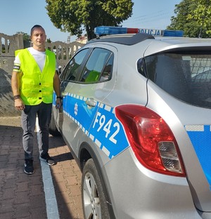 na zdjęciu policjant stoi przy radiowozie