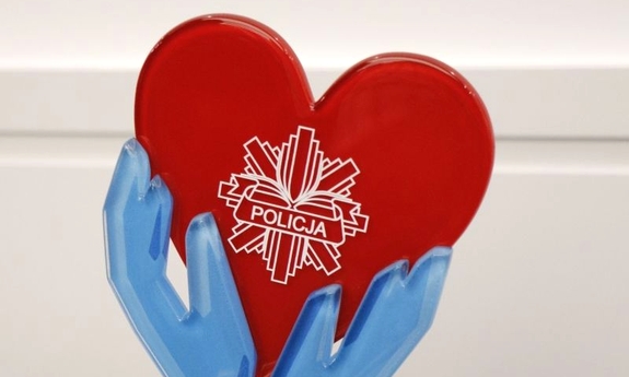 Fragment statuetki: Czerwone serce z logiem Policji trzymane w niebieskich dłoniach