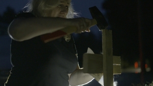 kadr z filmu: kobieta wbija krzyż młotkiem