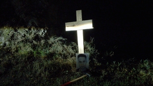kadr z filmu: krzyż przydrożny, o który oparte jest zdjęcie mężczyzny