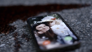 kadr z filmu: na drodze leży smartfon, na którego ekranie widać zdjęcie kobiety i dziecka oraz napis Żonka