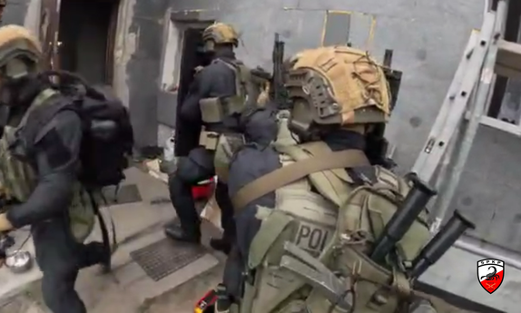 uzbrojeni funkcjonariusze w trakcie siłowego wejścia do budynku