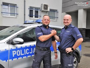 obok radiowozu stoją dwaj policjanci