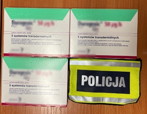 trzy opakowania z plastrami i opaska z napisem Policja