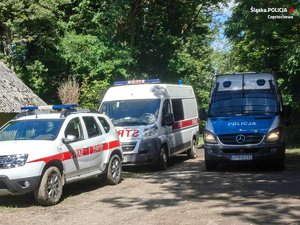 na zdjęciu radiowóz policyjny i dwa radiowozy strażackie w terenie