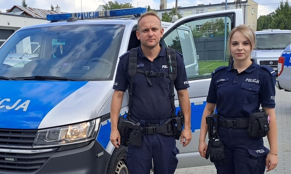 policjant i policjantka przy radiowozie