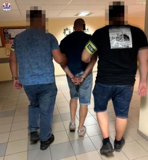 dwaj policjanci prowadzą zatrzymanego mężczyznę