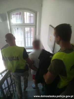 policjanci idą z zatrzymanym po schodach