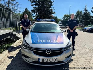 dwóch policjantów stoi przy radiowozie