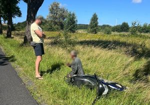 policjant i kierujący skuterem w rowie