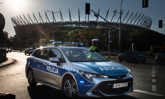 radiowóz policyjny stoi przed stadionem narodowym w Warszawie, obok radiowozu policjant