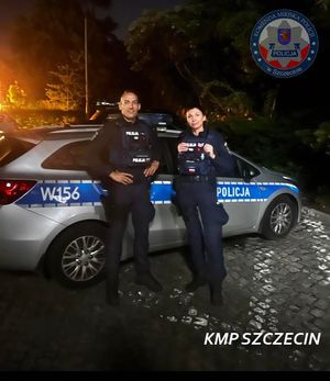 noc, policjanci stoją obok radiowozu