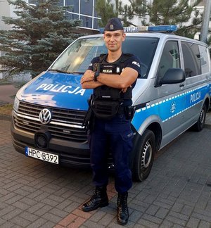 policjant stoi przy radiowozie