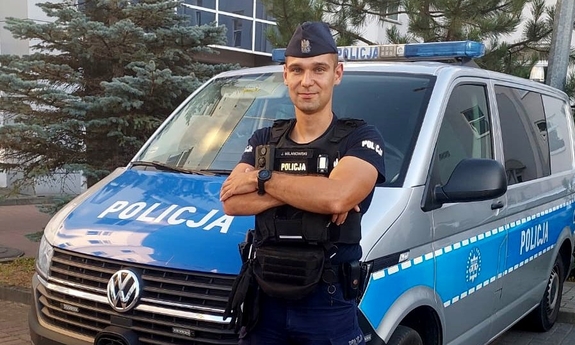 policjant stoi przy radiowozie